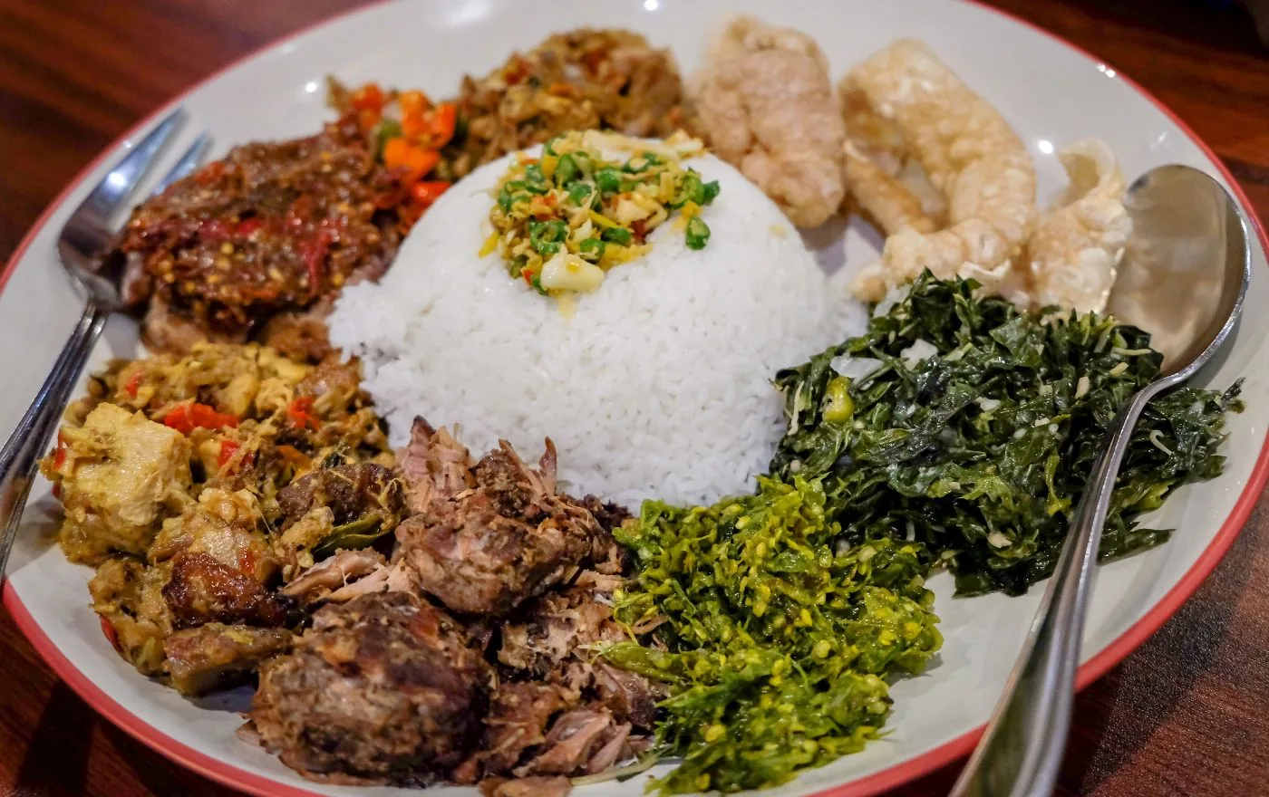Babi Guling suckling pig with crispy golden skin served with rice, lawar, and sambal at a Balinese warung