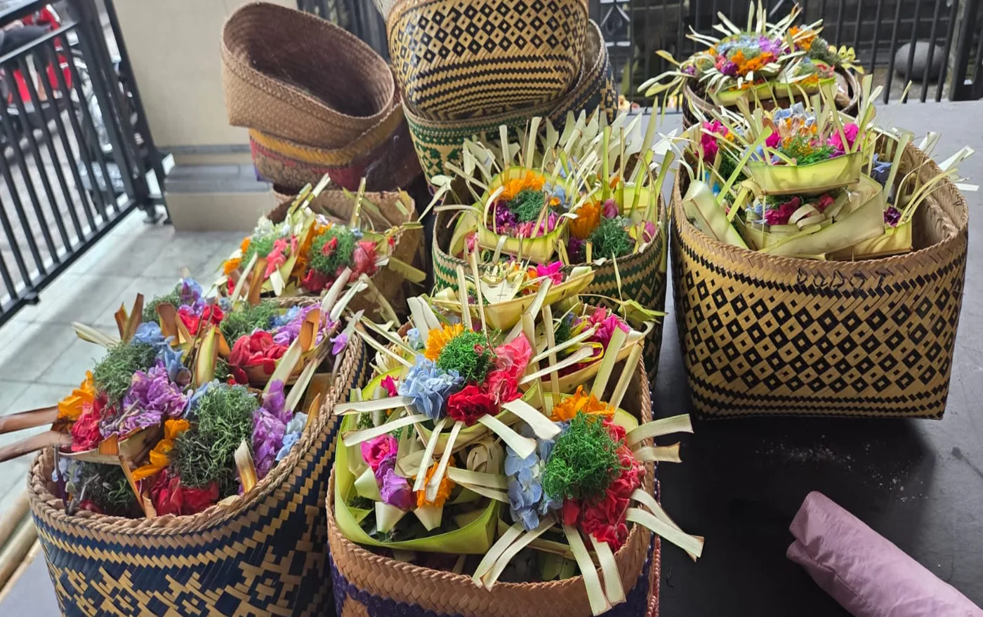 Colorful canang sari offerings with fresh flowers in traditional woven baskets prepared for a Balinese temple ceremony