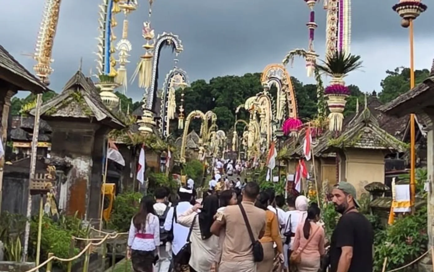 Penjor bamboo poles decorated with golden ornaments lining the main street of Penglipuran Village in Bali during the Galungan festival