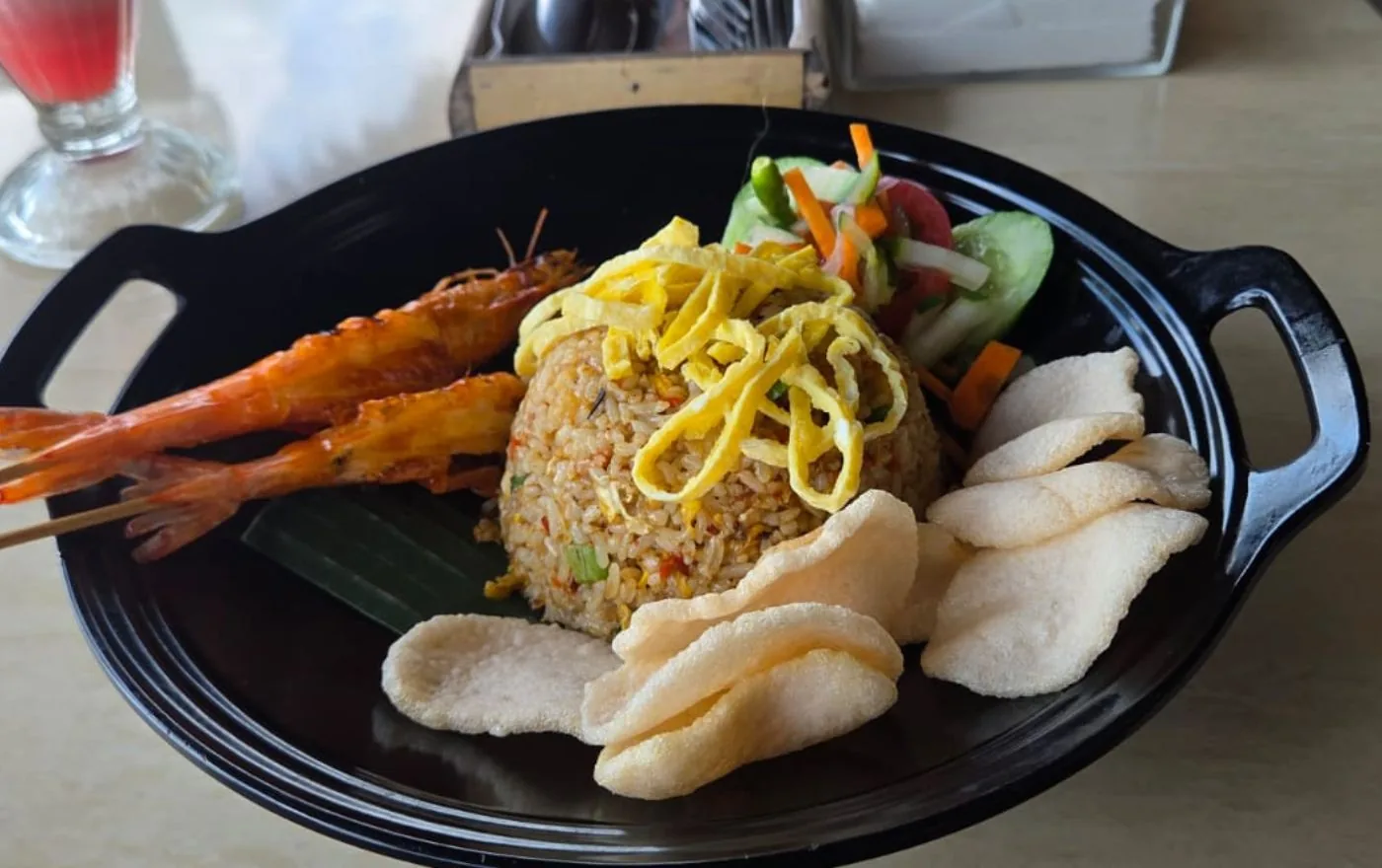 Nasi Goreng Indonesian fried rice topped with a shrimp skewer, fried egg, and kerupuk
