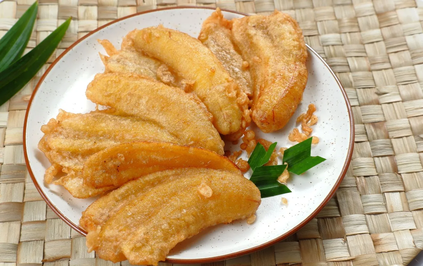 Pisang Goreng golden crispy fried bananas stacked on a plate, fresh from the fryer